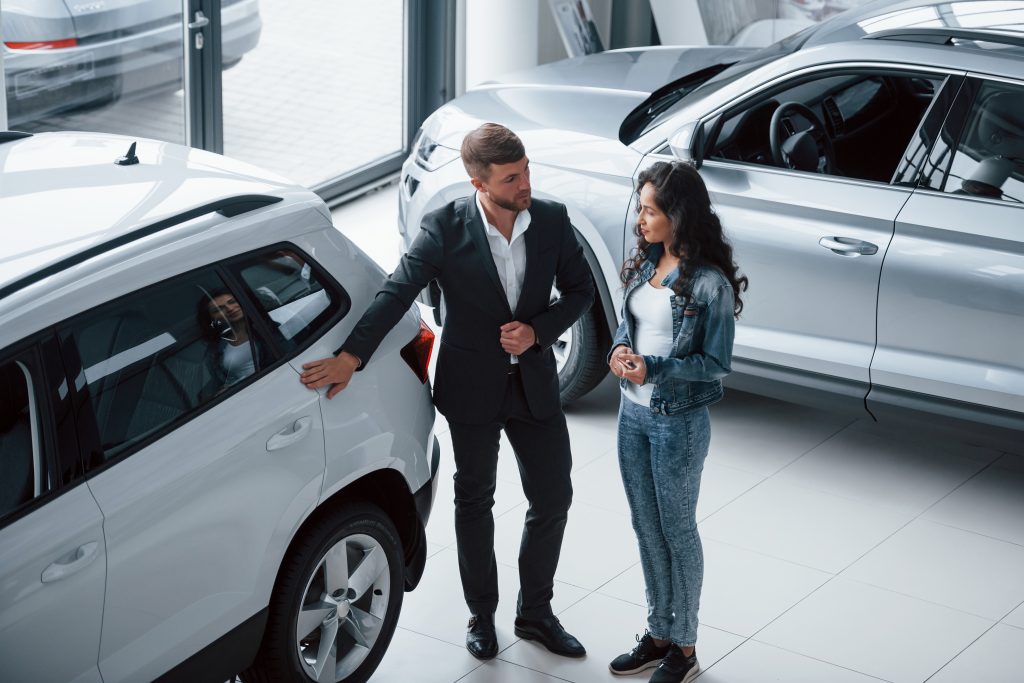 Perfect choise. Female customer and modern stylish bearded businessman in the automobile saloon